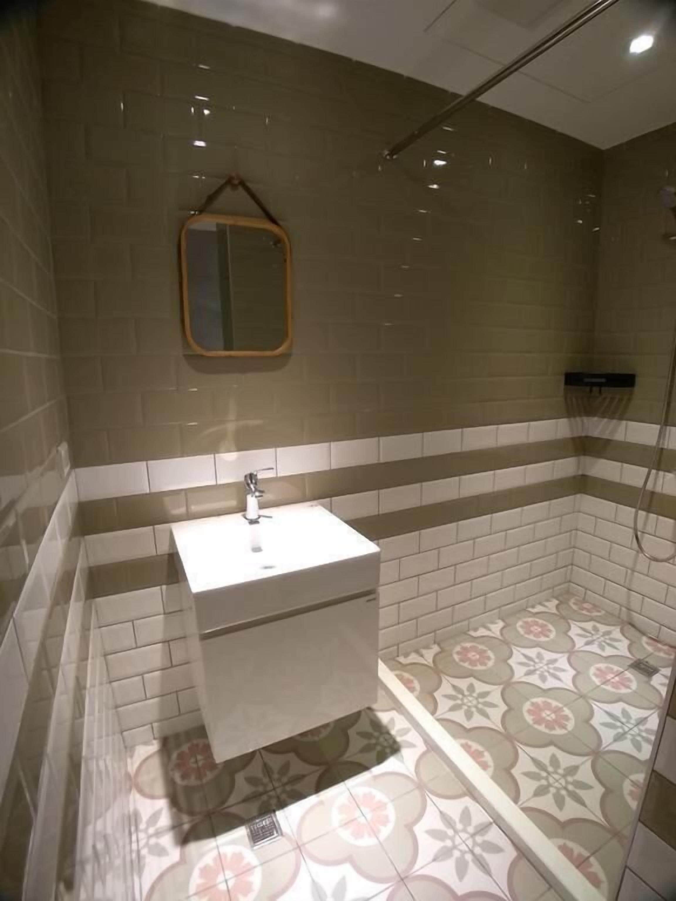 A bathroom with a white sink, a mirror, and patterned floor tiles.