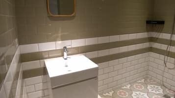 A bathroom with a white sink, a mirror, and patterned floor tiles.