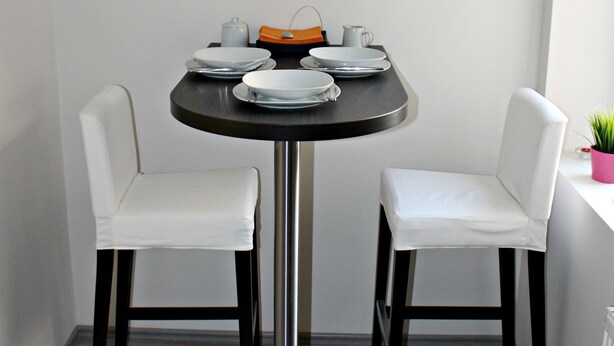A small dining area with a round table, two white chairs, a black pendant light, and a potted plant. - Baltazar Studio Apartment (Zagreb)