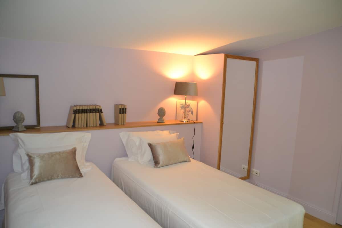 A bedroom with two single beds, a bedside table with a lamp, and a mirror on the wall.