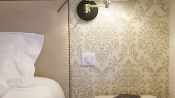 Una cama bien hecha con un cojín blanco y una mesita de noche con una lámpara y un libro.