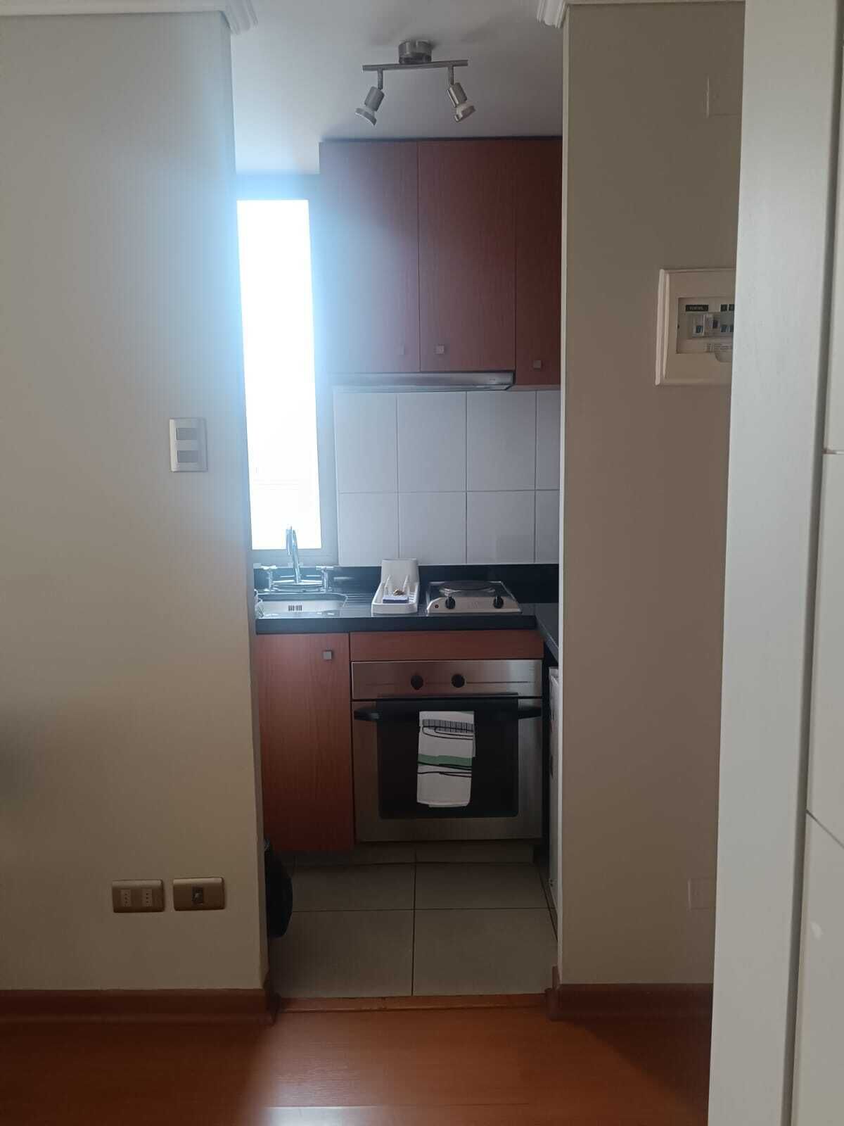 Een keuken met houten kastjes, een fornuis en een raam.