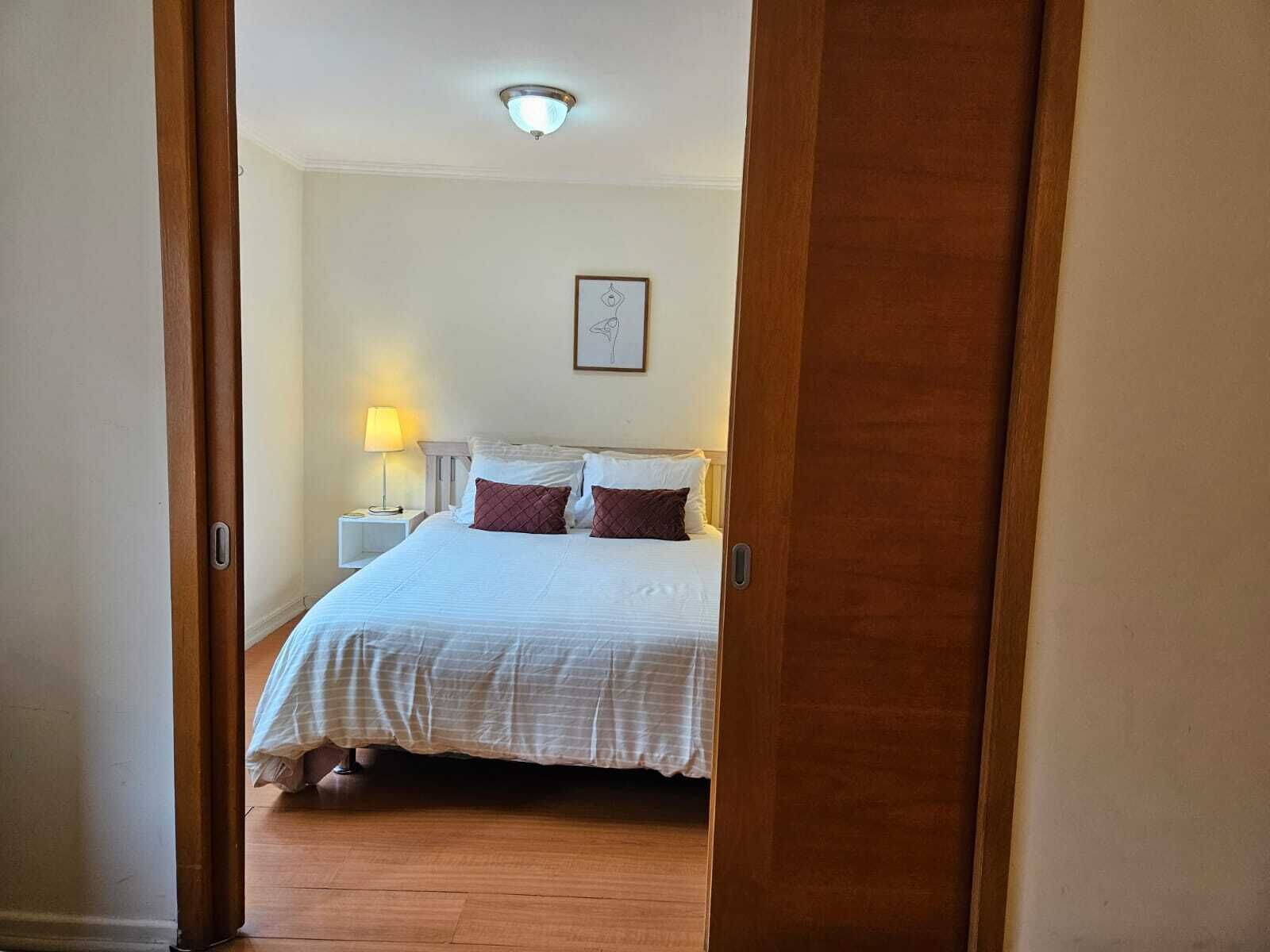A bedroom with a bed, a nightstand, a lamp, and a ceiling light.