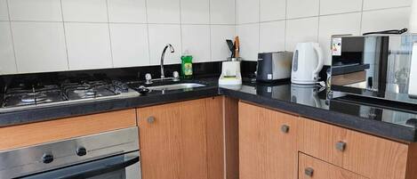 A modern kitchen with a gas stove, oven, stainless steel appliances, and wooden cabinets.