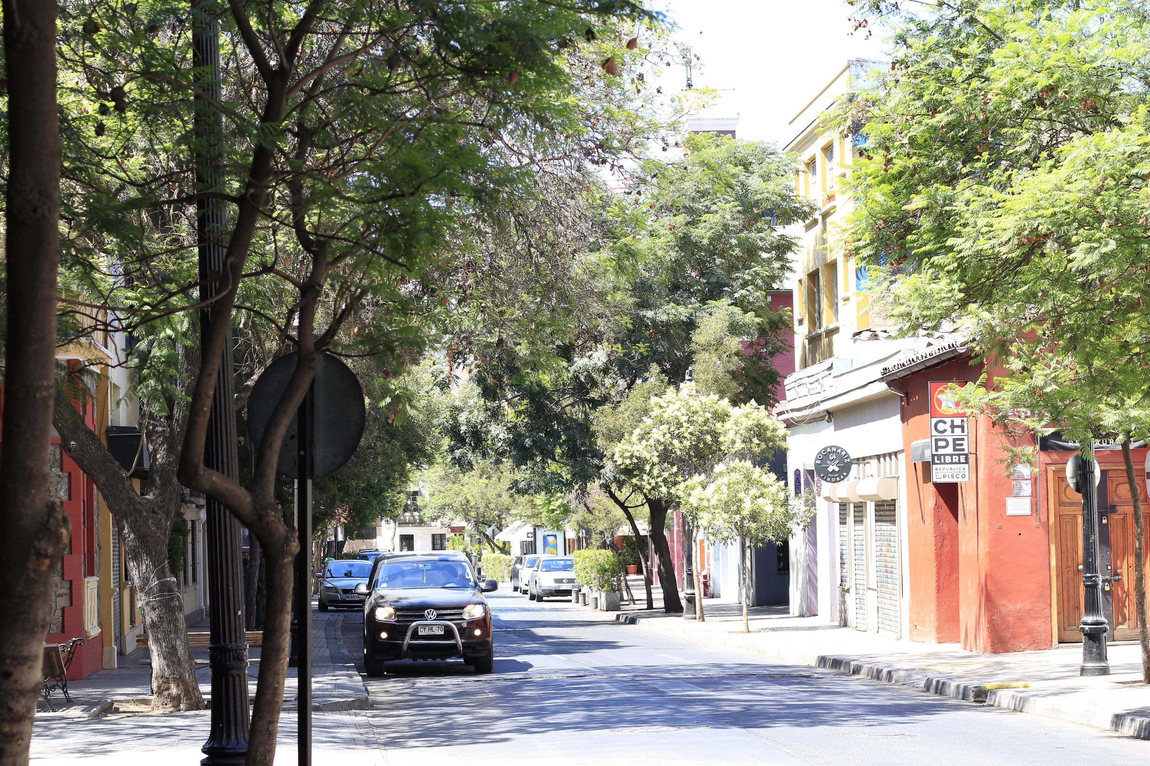 Une rue bordée d’arbres et d’immeubles, dont un restaurant dont l’enseigne indique « CH DE LIBRE ».