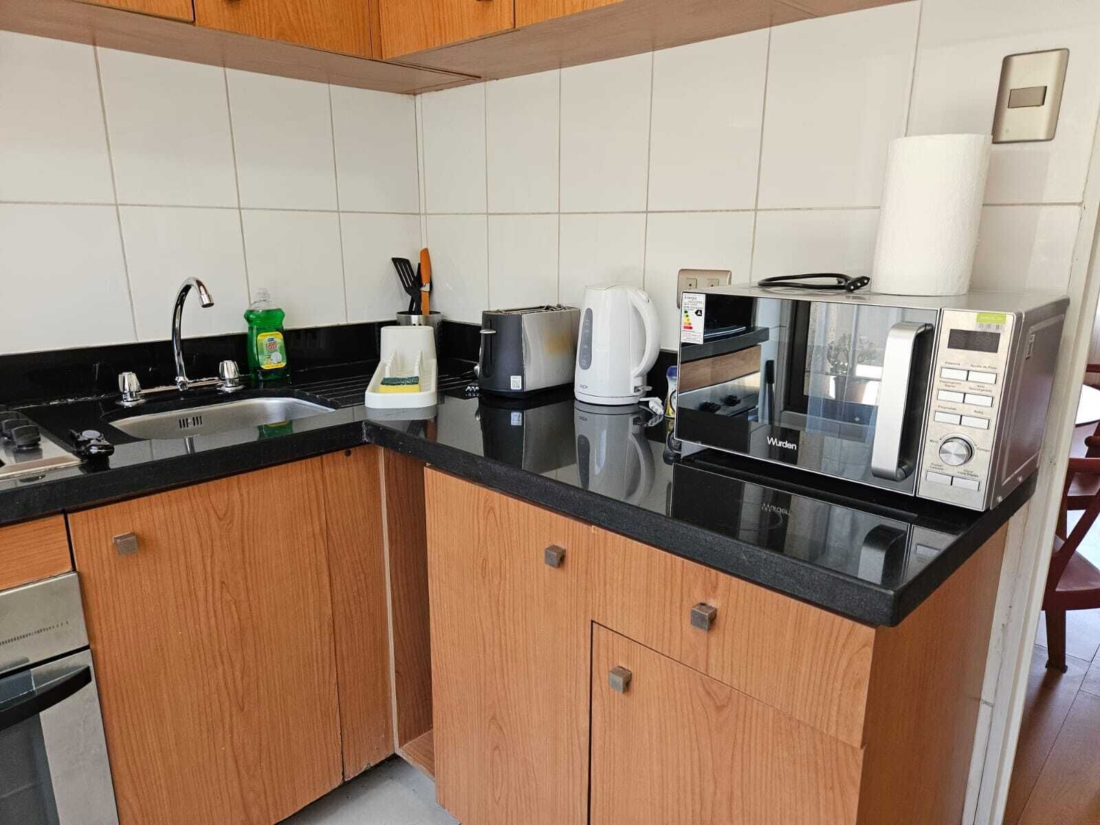 A compact kitchen with a sink, a coffee maker, a toaster, and a microwave.