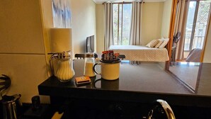 Een hotelkamer met een bed, een koffiezetapparaat, zout- en peperstel en een raam met gordijnen.