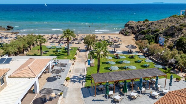 Un complexe hôtelier de bord de mer avec des chaises longues, des parasols et un espace piscine.
