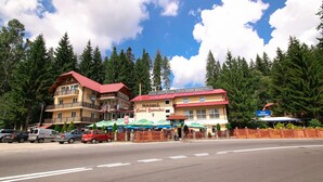 Ein Hotel mit rotem Dach und mehreren Balkonen, umgeben von Bäumen.