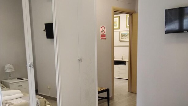 A hotel room with a bed, a wardrobe, a small table, and a chair. - B&B Fratelli Nicoli (Rome)