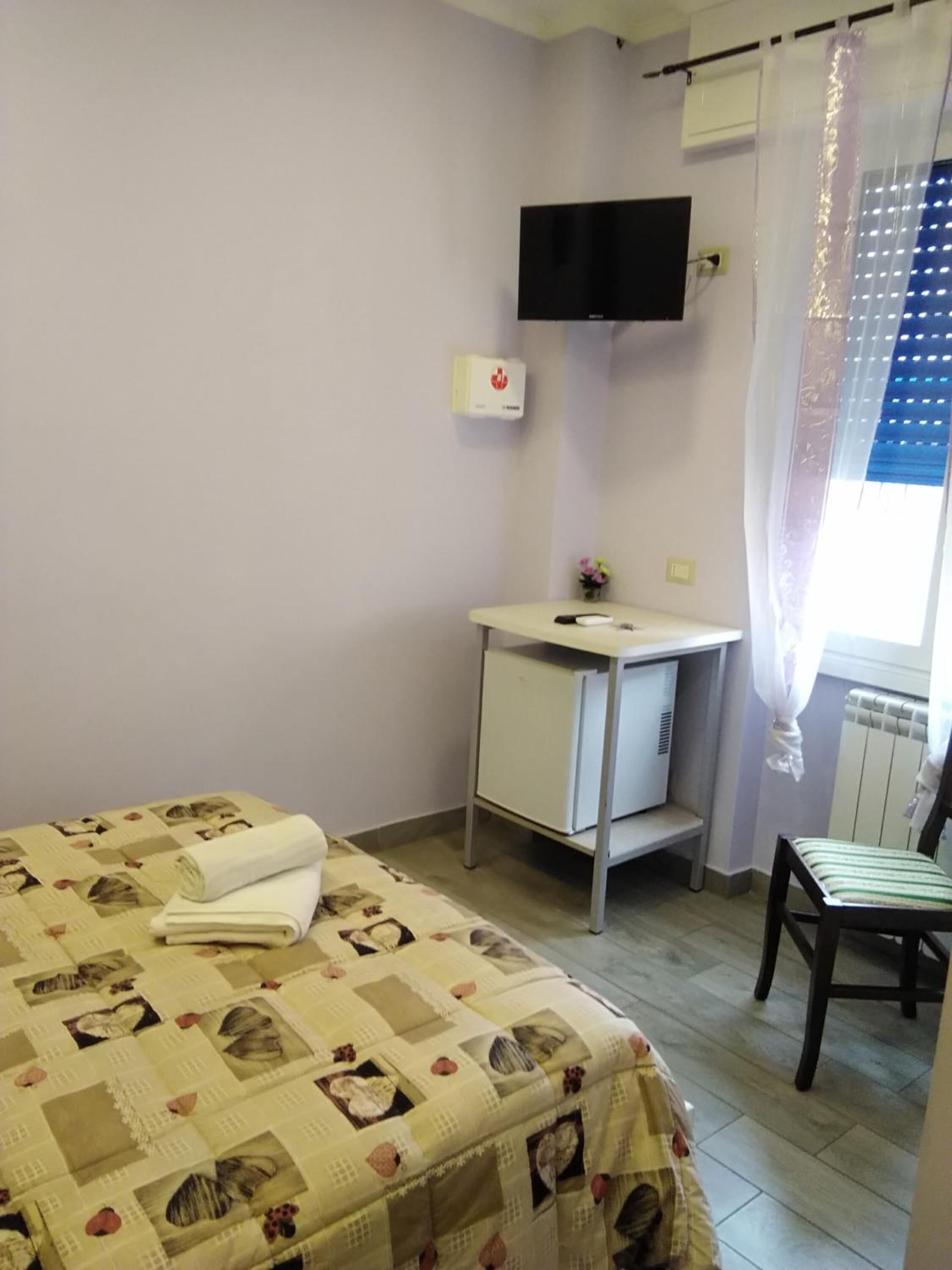 Une chambre à coucher avec un lit, un bureau, une chaise, un téléviseur et un radiateur.
