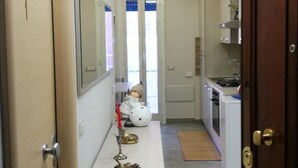 A narrow hallway leading to a kitchen with a white countertop, a small decorative item, and a doll. - B&B Fratelli Nicoli (Rome)