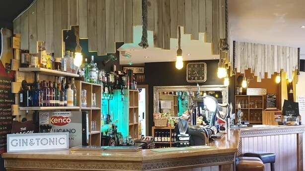 A bar area with stools, shelves of bottles, and a sign for gin & tonic. - Peniarth Arms Hotel (Tywyn)