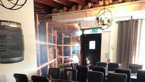 A restaurant with multiple tables and chairs, a menu board on the wall, and a decorative ceiling. - Peniarth Arms Hotel (Tywyn)