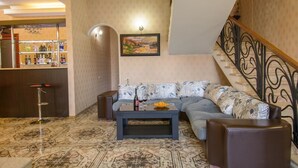 A living room with a sofa, coffee table, and a bar area with shelves.
