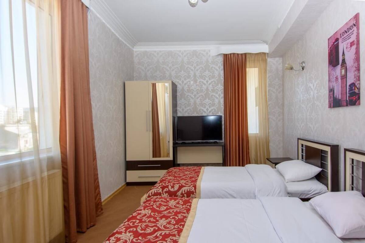 A hotel room with two beds, a TV, a wardrobe, and a poster on the wall.