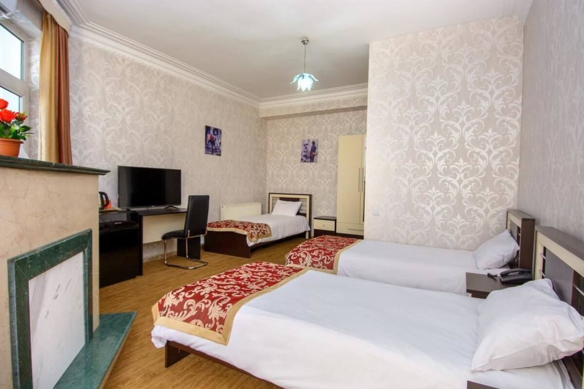 A hotel room with two beds, a desk, a chair, a TV, and a mirror.