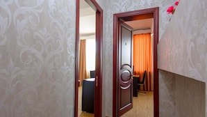 A hotel room with a wooden door, a black suitcase, and a chair.