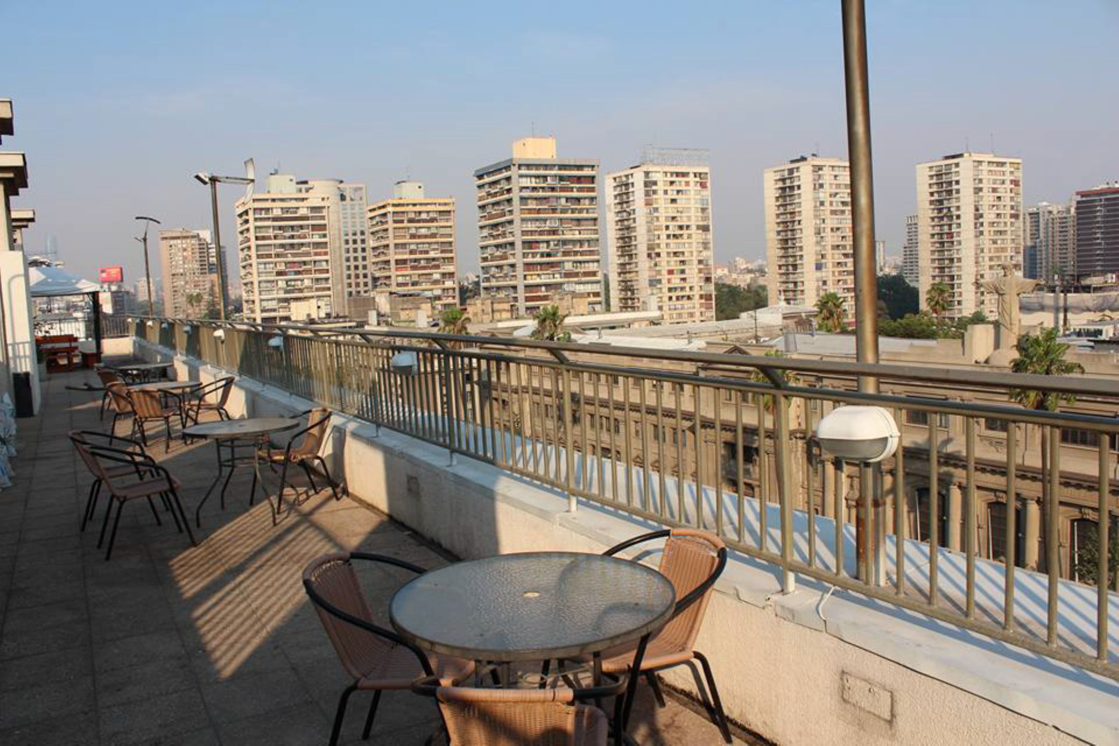 Eine Terrass mit Tischen und Stühlen mit Blick auf eine Skyline mit Hochhäusern.