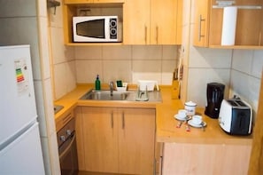 A compact kitchen with a microwave, sink, and basic appliances.