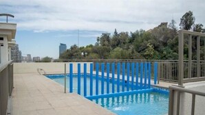Une piscine sur le toit, bordée de bleu et dotée d’une rambarde en métal.