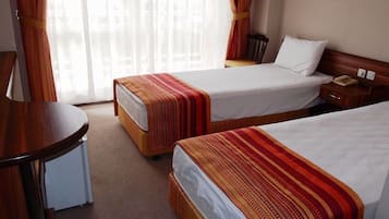 Ein Hotelzimmer mit zwei Betten, einem Schreibtisch und einem Stuhl.