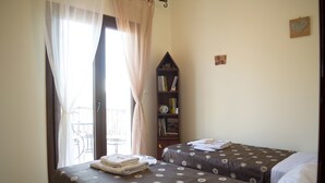 Habitació amb dos llits, una estanteria i un balcó.