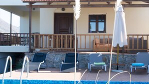 Zona de piscina amb gandules i una pèrgola.