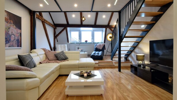 A modern living room with a sofa, a coffee table, a TV, and a staircase. - Libertas Apartment Zagreb (Zagreb)