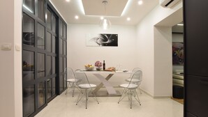 A modern dining area with a glass partition, a table with chairs, and a pendant light. - Libertas Apartment Zagreb (Zagreb)