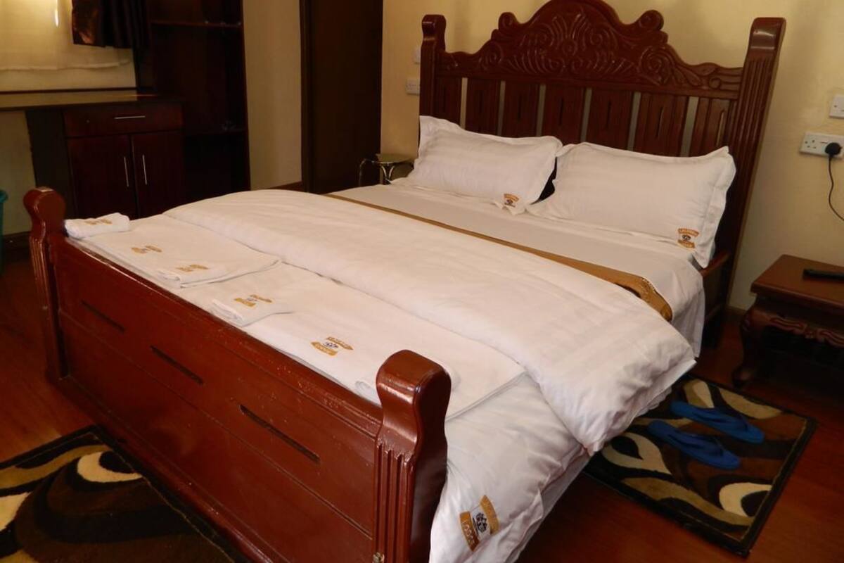 A wooden bed with white bedding, a nightstand, and a patterned rug.
