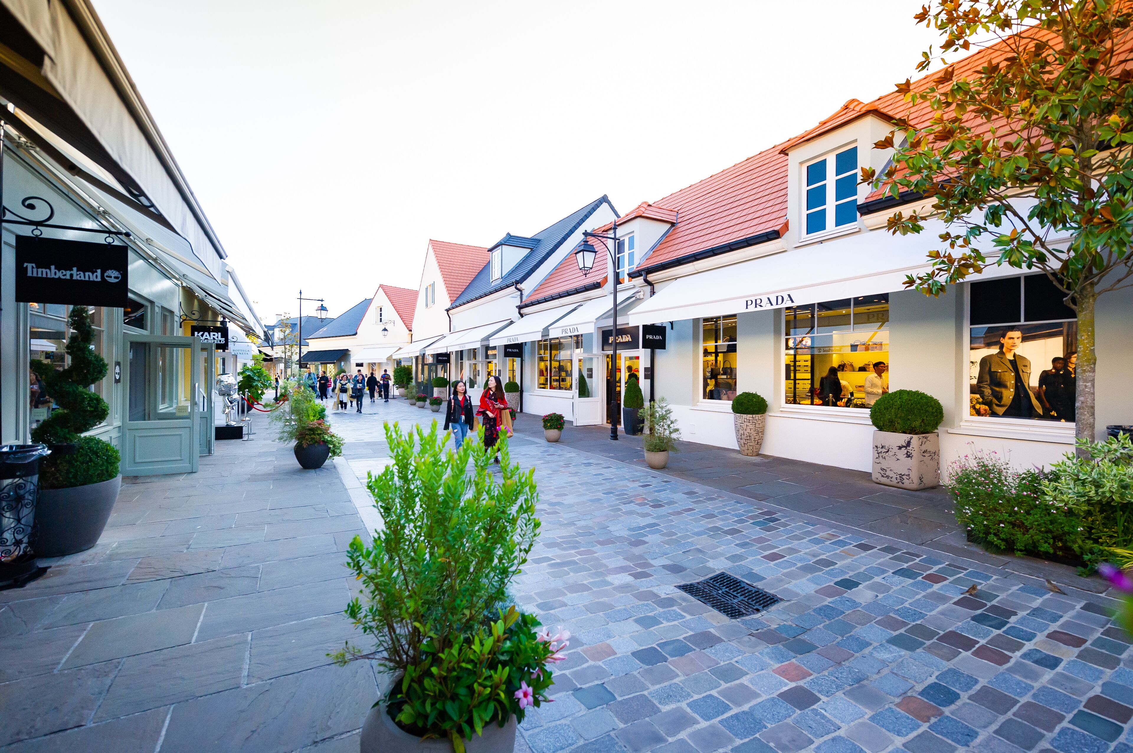 A pedestrian street lined with shops, including a visible 'Timberland' store.