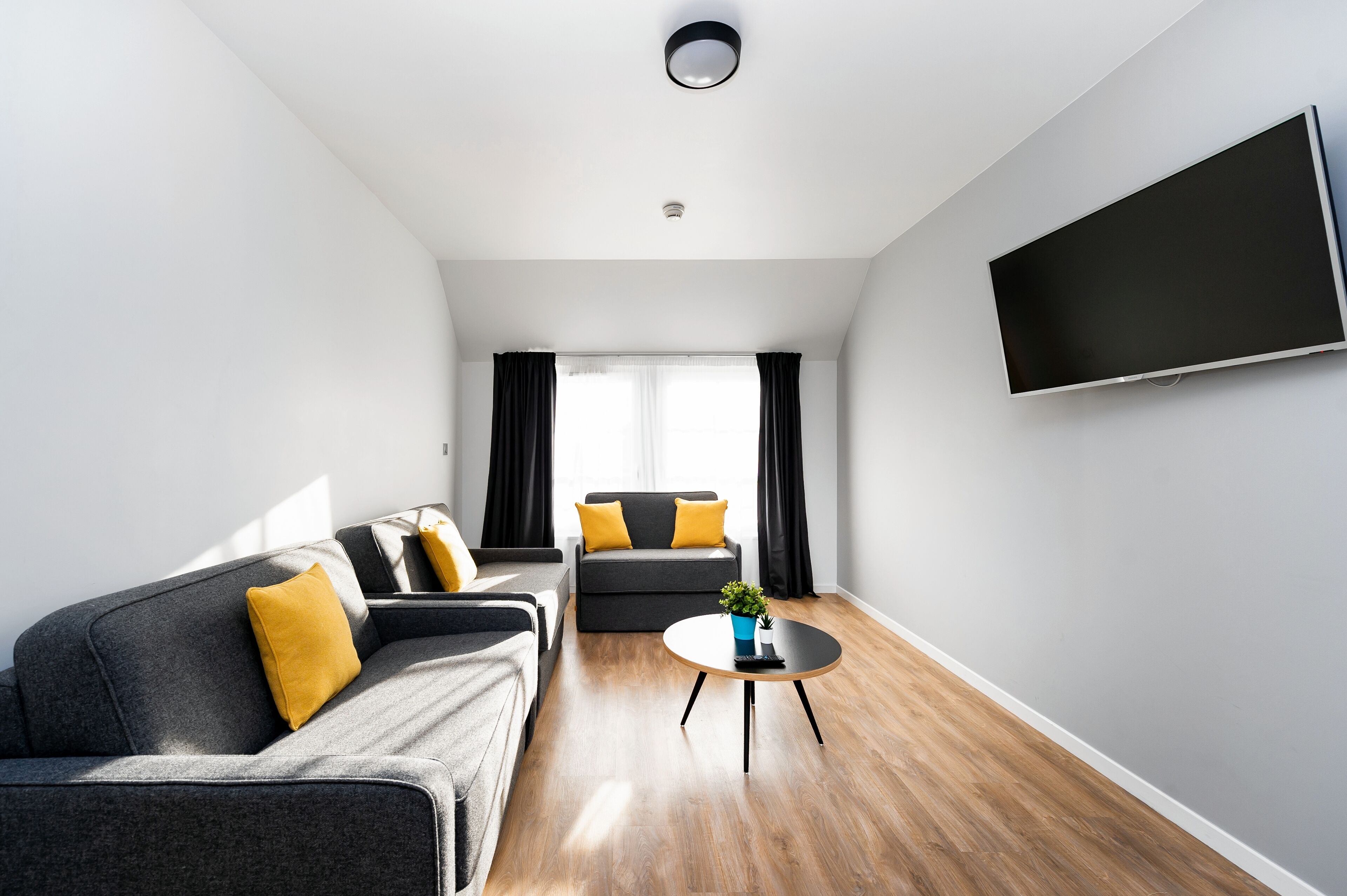 A modern living room with a grey sofa, a black armchair, and a coffee table.