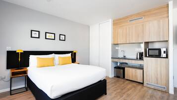 Una camera d'albergo moderna con un letto grande, un angolo cottura piccolo e un bagno.