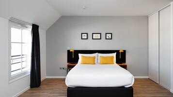 Un dormitorio moderno con una cama grande, una ventana con cortinas, un cabecero con dos lámparas y tres cuadros en la pared.