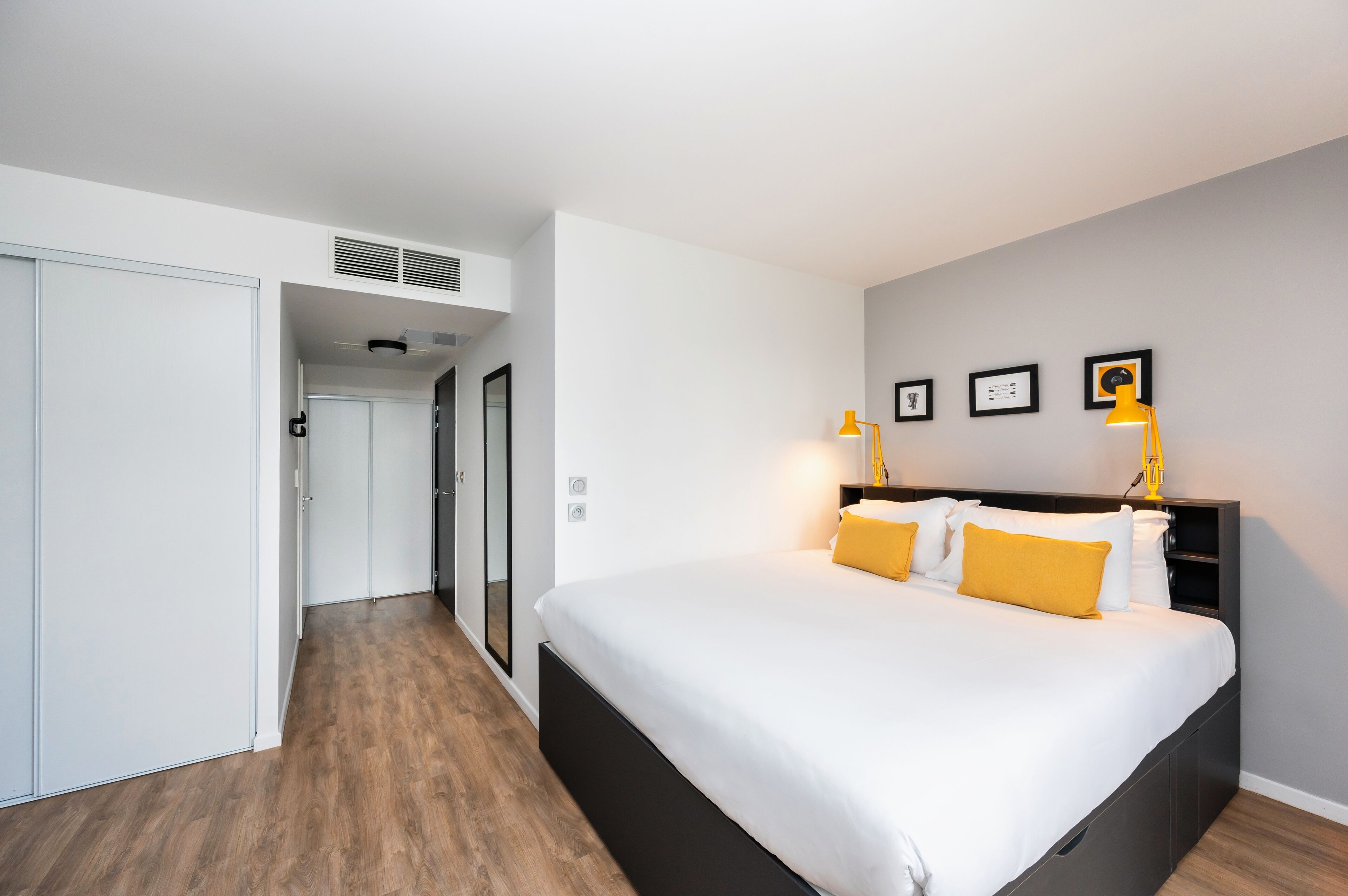Quarto moderno com uma cama grande, um guarda-roupa e um corredor que dá para outro espaço.