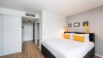 Quarto moderno com uma cama grande, um guarda-roupa e um corredor que dá para outro espaço.