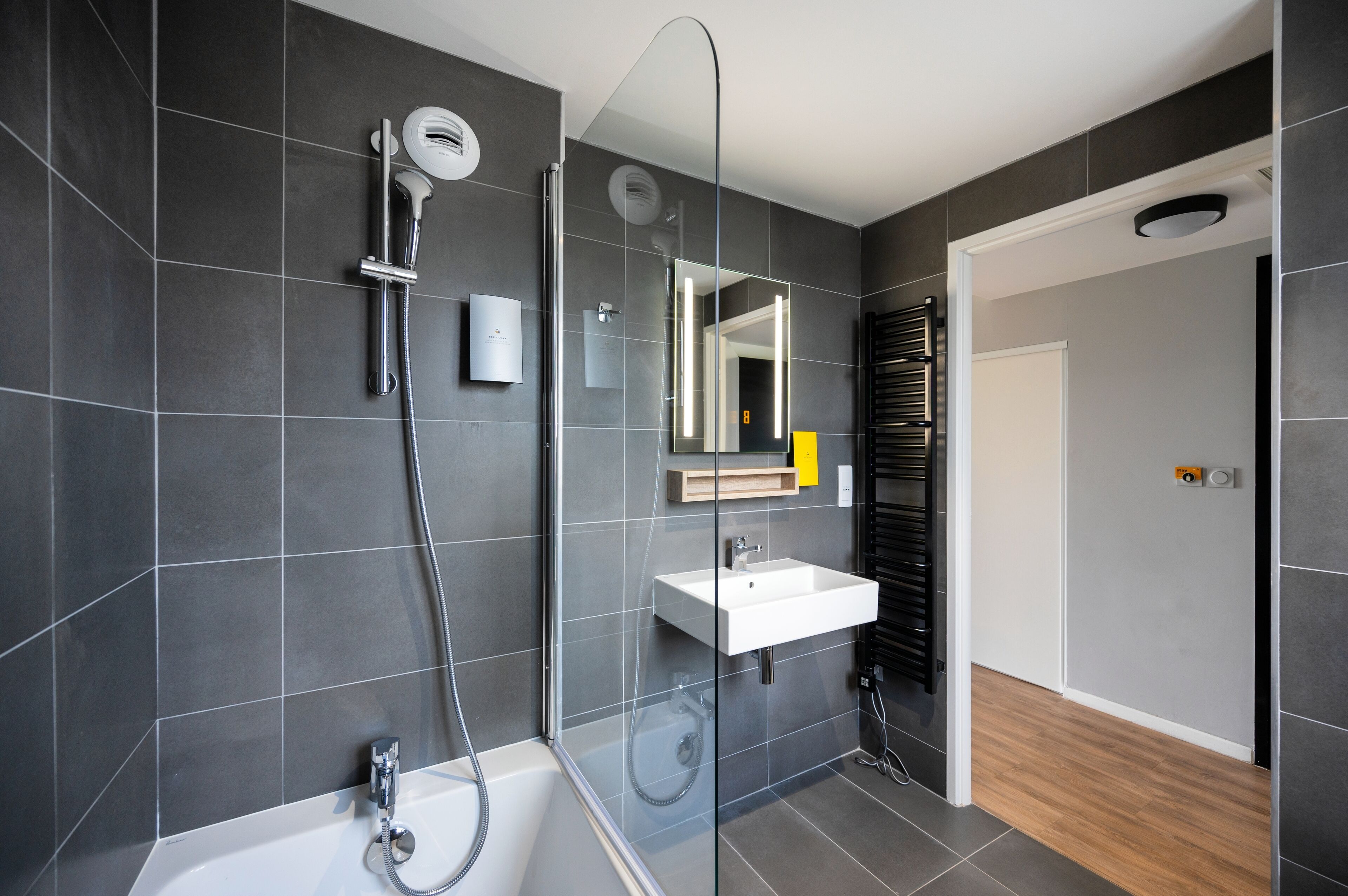 A modern bathroom with a glass-enclosed shower, a white sink, and a mirror above it.