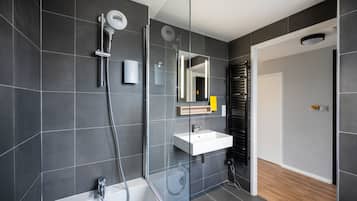 A modern bathroom with a glass-enclosed shower, a white sink, and a mirror above it.