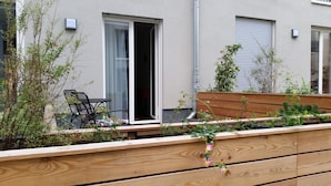 A balcony with a wooden bench, a table with chairs, and a window with a sliding door. - Apartment P1 in Berlin-Friedrichshain (Berlin)