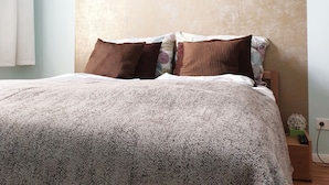 A bedroom with a bed, pillows, a nightstand, and a wall with a textured pattern. - Apartment P1 in Berlin-Friedrichshain (Berlin)