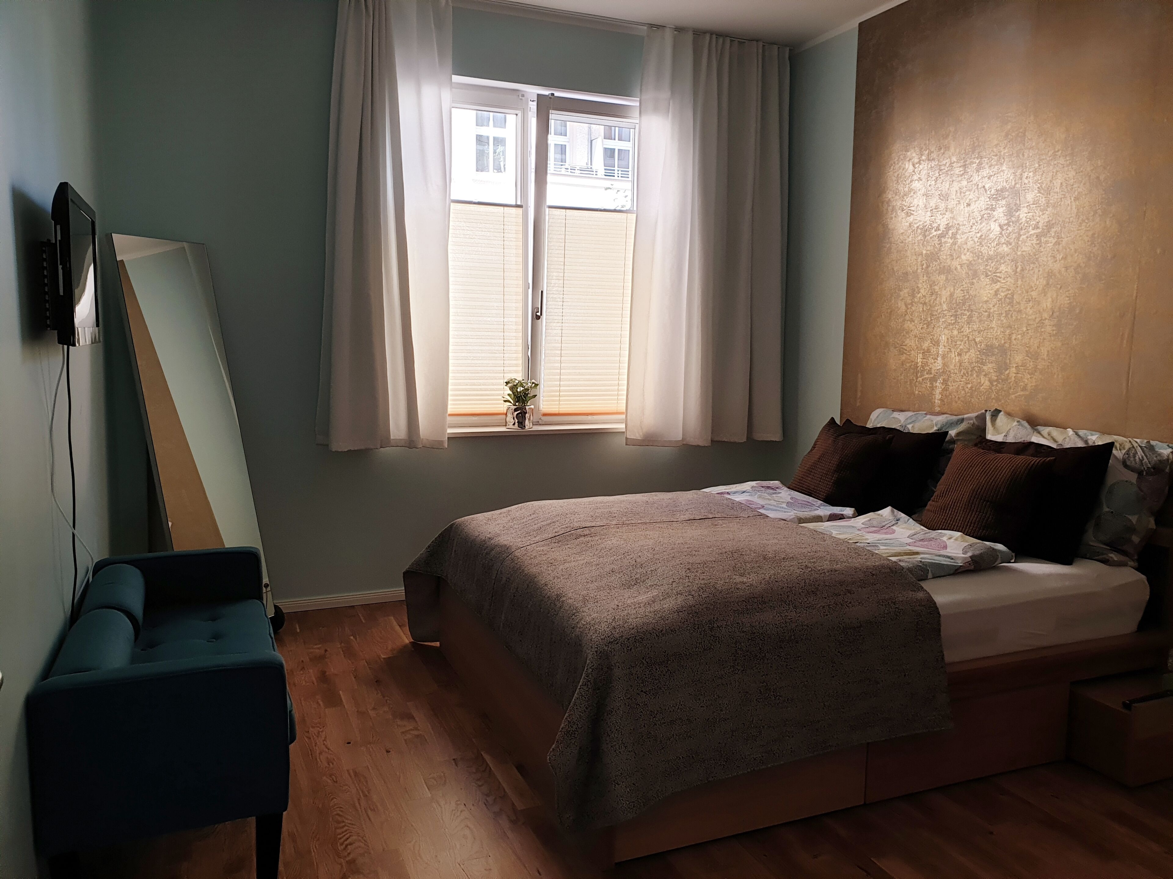 Ein Schlafzimmer mit einem Bett, einem Schreibtisch und einem Fenster mit Vorhängen.