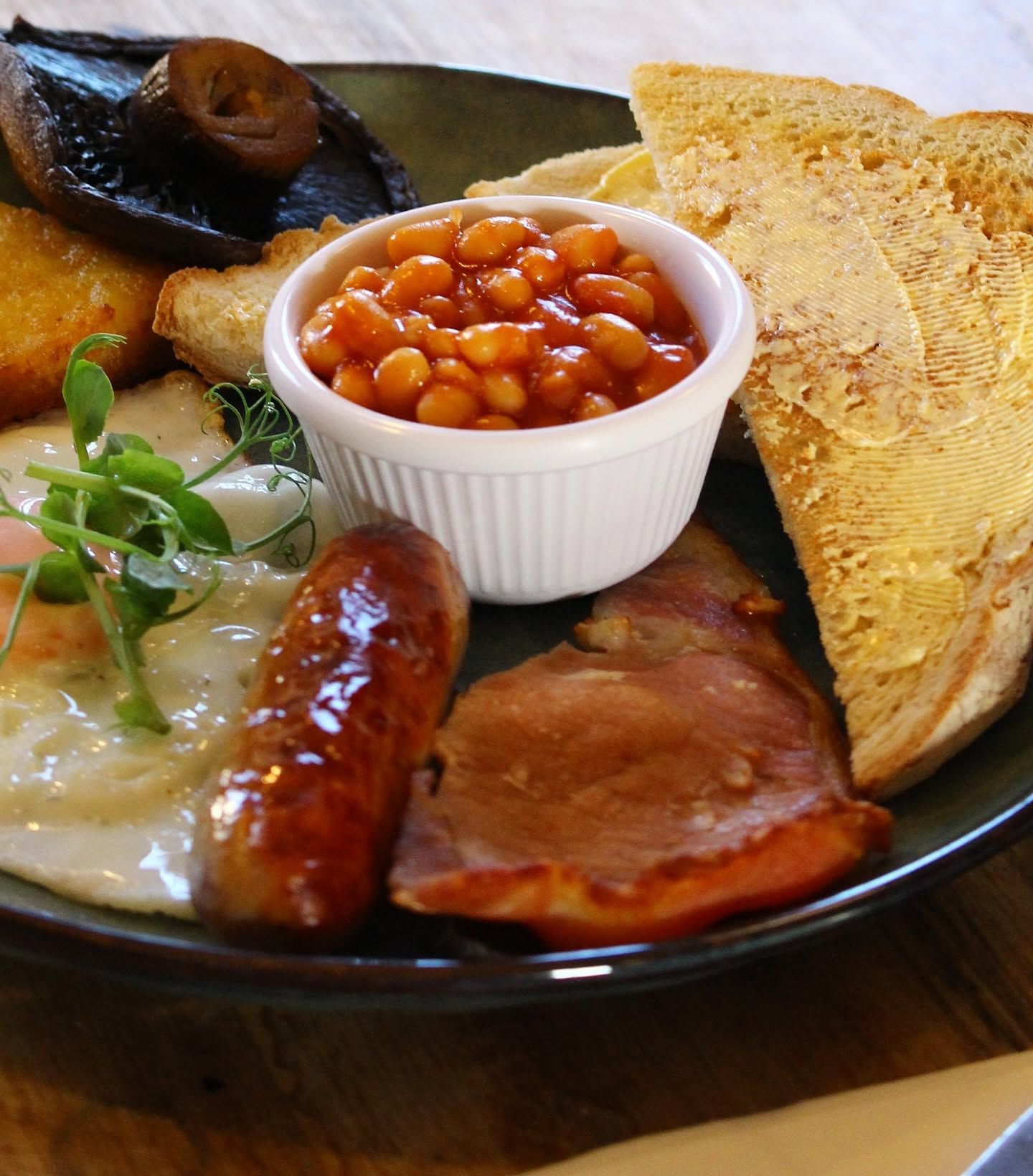 A plate of food including beans, toast, sausages, and ham.