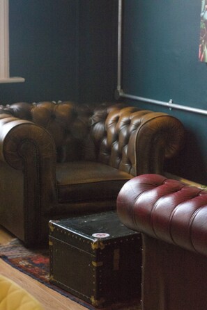 A room with a dark brown leather sofa, a matching armchair, and a small black chest of drawers. - The Great Western Hotel (Taunton)