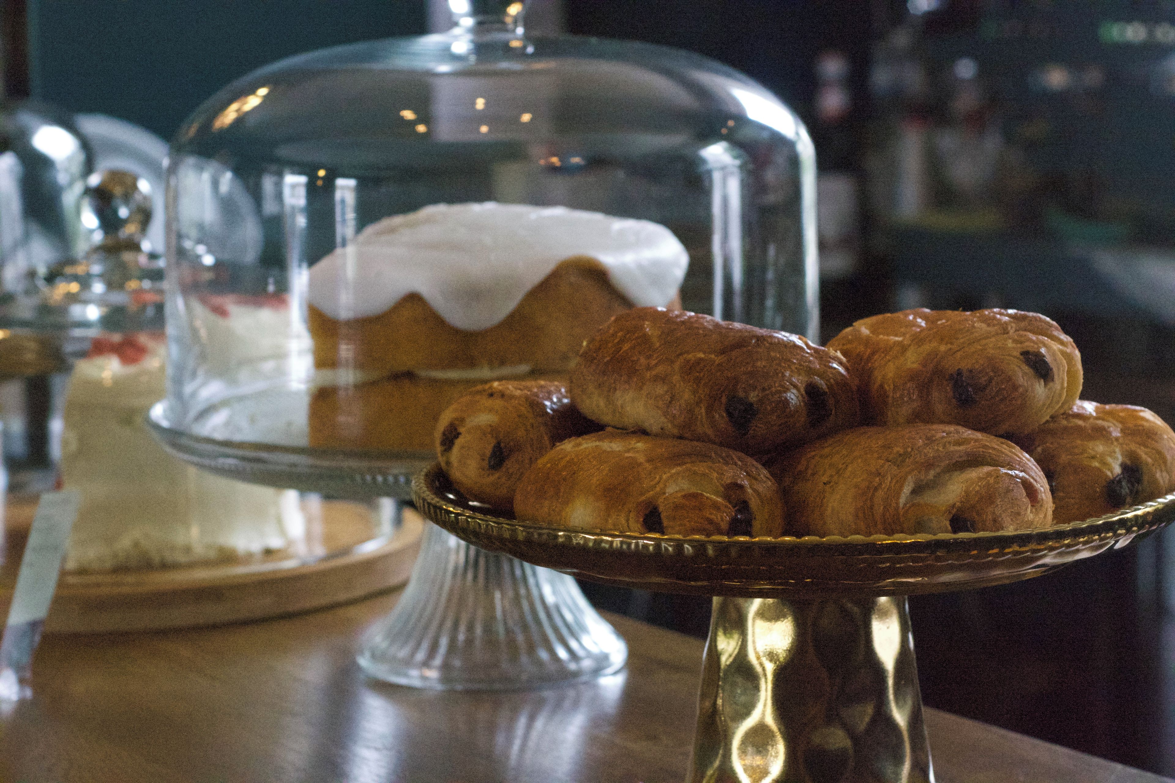 Presentació de postres amb pastissos i un pastís sota una cloche de vidre.