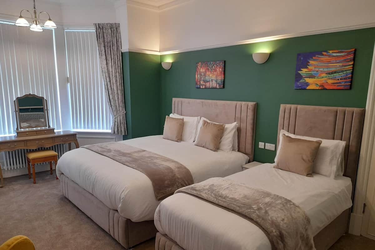 A hotel room with two beds, a desk, and a chair.