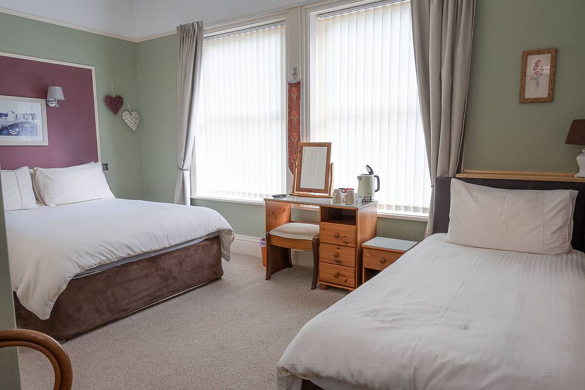 A bedroom with two beds, a desk, and a chair.