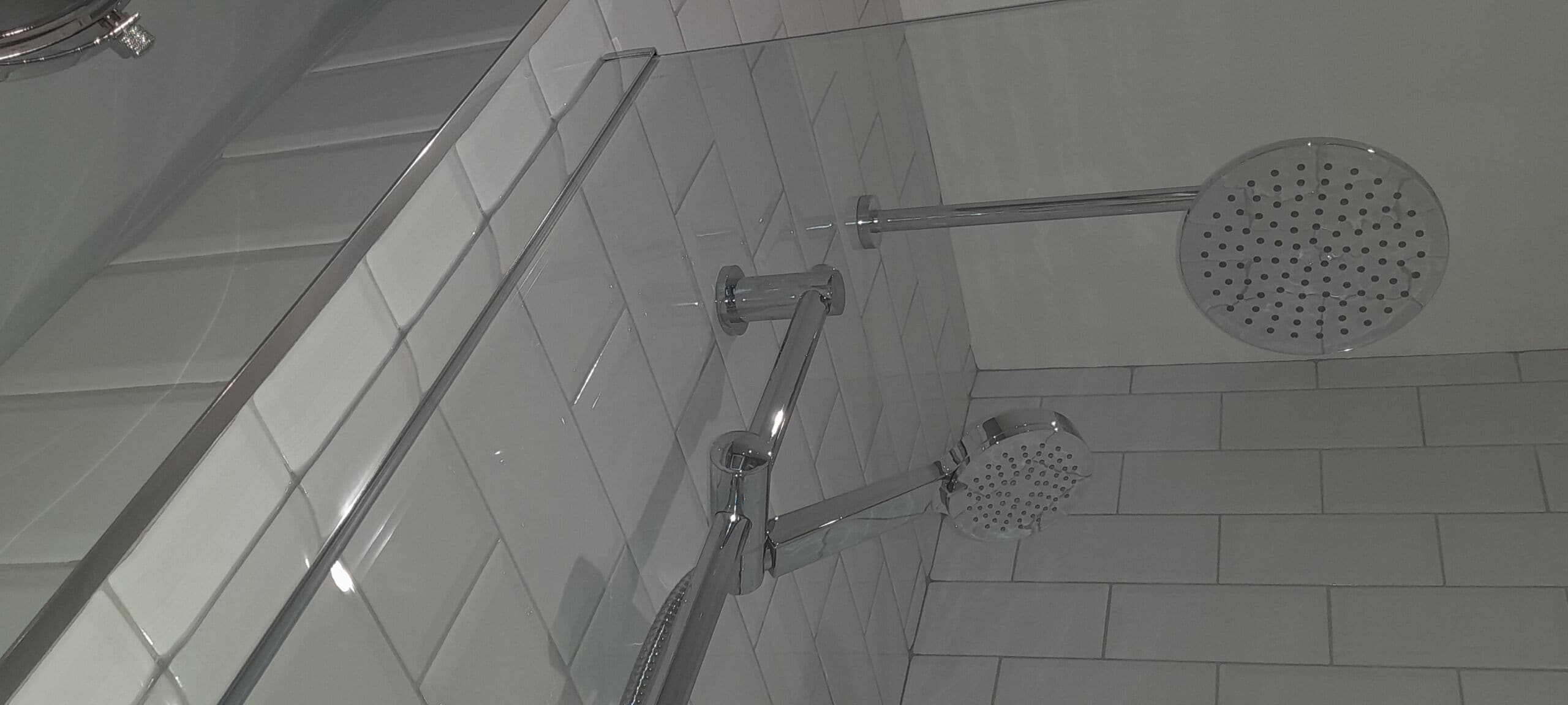 A shower with a handheld showerhead and a fixed wall-mounted showerhead.