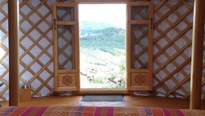 Una yurta con una puerta de madera que da a un paisaje montañoso.