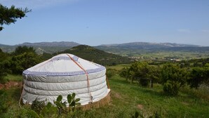 Una yurta en un campo cubierto de hierba con montañas al fondo.